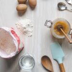 bag of flour, eggs, measuring cups, and cooking utensils on the counter