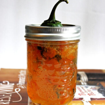 pepper jelly in a jar, placed on top of a cookbook