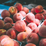 bushels of peaches on a table with a stream of light shining on them