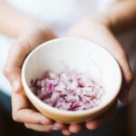 hands holding a bowl of chopped onions