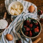 bowls of butter and strawberries on a dish towel on a wooden table