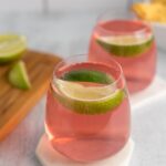 two glasses filled with pink jello topped with lime slices