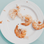 fresh shrimps on a white plate, sitting on a blue table