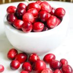 white bowl full of cranberries on a white plate