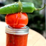 jar of tomato jam with a tomato, jalapeno and honey drizzle on top