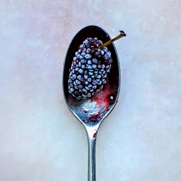 blackberry on a silver sppon on a marble counter top
