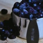 metal measuring cup overflowing with frozen blueberries