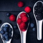 three spoons holding blueberries, raspberries, and blackberries