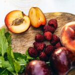 peaches and raspberries on a wooden cutting board