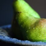 two green pears on a blue pottery bowl