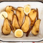 Container of halved pears with fresh lemons and sprinkled with cinnamon