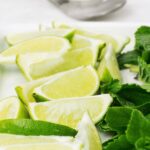 sliced limes and bright green mint on a white countertop