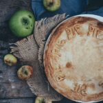apple pie on a rustic table surrounded by apples