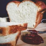 loaf of fresh white bread sliced next to a dollop of grape jelly