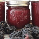 jars of blackberry jam with fresh blackberries in front