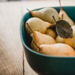 pears in a teal bowl on a wooden table