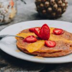 pineapple and strawberries topping a plate of buckwheat pancakes