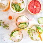 glasses of lemonade surrounded by ingredients on a kitchen counter