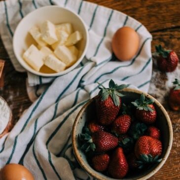 bowl of cubed butter next to a bowl of fresh strawberries surrounded by a kitchen towel